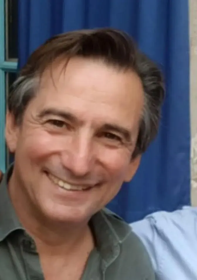 Portrait souriant d'un homme brun grisonnant en chemise verte