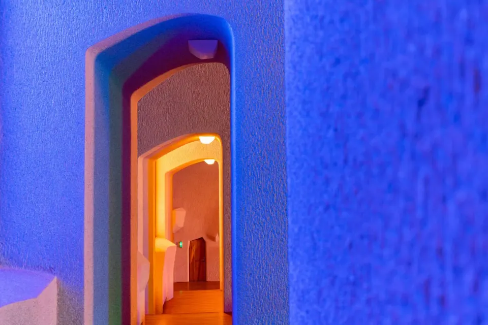 Passage voûté bleu ouvrant sur un couloir orangé