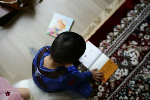 Enfant vu de haut lisant un livre au sol