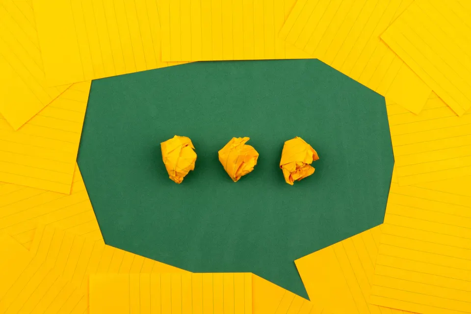 Bulle de dialogue verte et papiers jaunes froissés