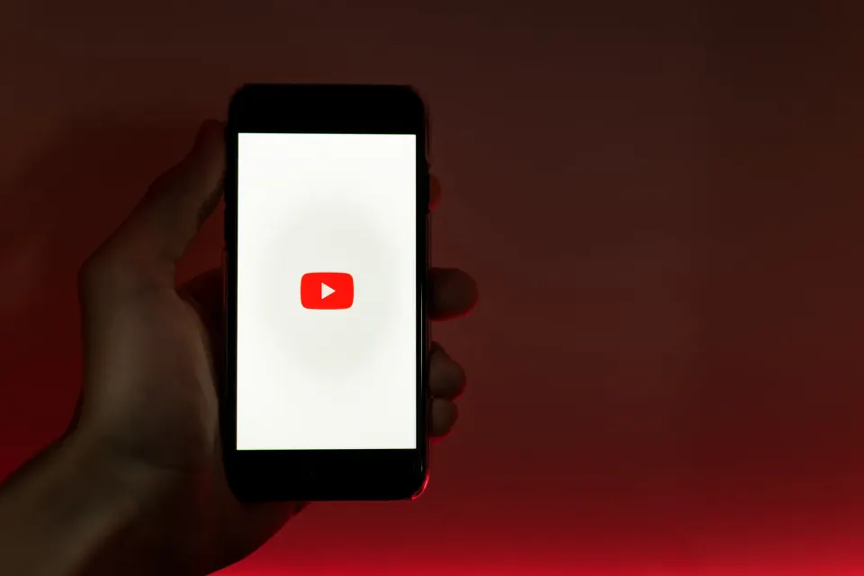 Main tenant un téléphone affichant le logo YouTube
