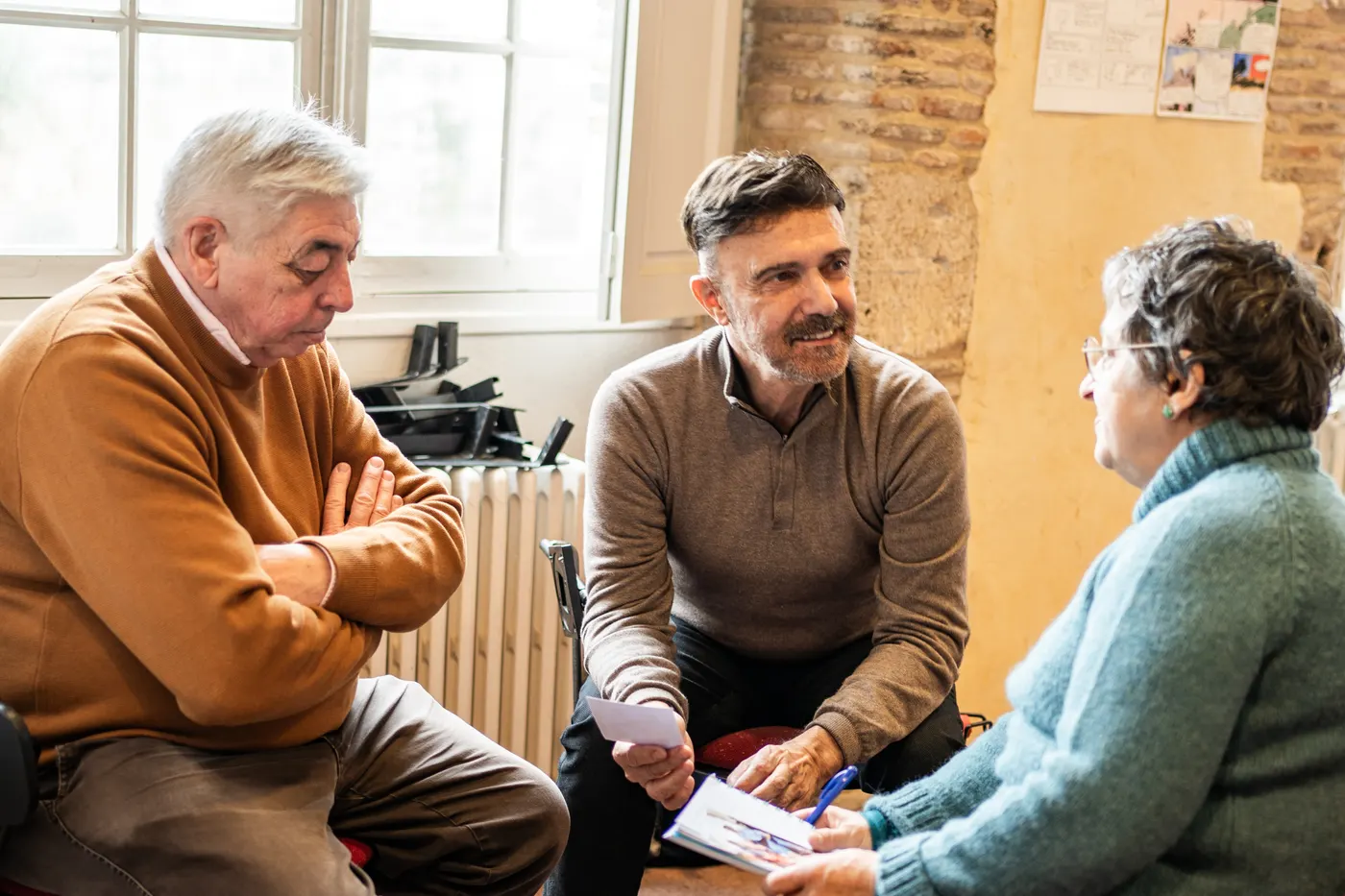 Trois personnes en discussion assise, papiers en main